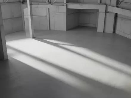Minimalistische, leerstehende Industriehalle mit klaren geometrischen Schattenwürfen auf einem Betonboden. - Foto: über boerse-global.de