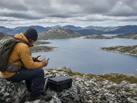 Geologe bei der Untersuchung von Gesteinsproben in einer abgelegenen kanadischen Landschaft nahe einem See. - Foto: über boerse-global.de