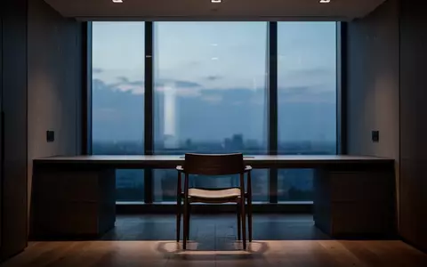 Ein minimalistischer, leerer Arbeitsplatz in der Abenddämmerung mit Blick durch ein Fenster. - Foto: über boerse-global.de