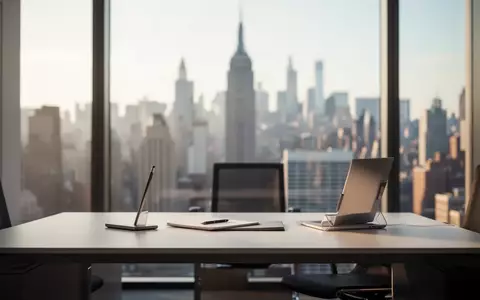 Modernes, minimalistisches BĂĽro mit verschwommener Skyline im Hintergrund und natĂĽrlichem Tageslicht. - Foto: ĂĽber boerse-global.de
