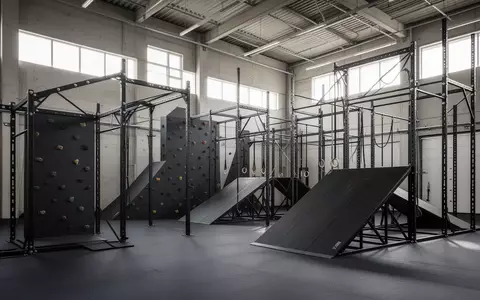 Moderne, leere Trainingshalle mit Hindernisparcours, Kletterstrukturen und Stahlrampen in einer hellen Industriehalle. - Foto: über boerse-global.de