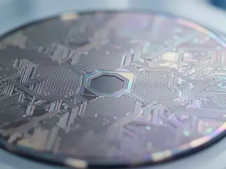 Mikroskopische Nahaufnahme einer siliziumbasierten Wafer-Oberfläche mit feinen geometrischen Strukturen und irisierenden Lichtreflexionen in einem Labor. - Foto: über boerse-global.de