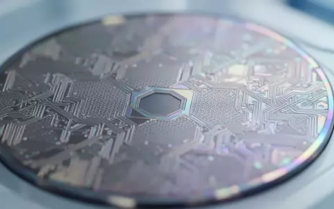Mikroskopische Nahaufnahme einer siliziumbasierten Wafer-Oberfläche mit feinen geometrischen Strukturen und irisierenden Lichtreflexionen in einem Labor. - Foto: über boerse-global.de