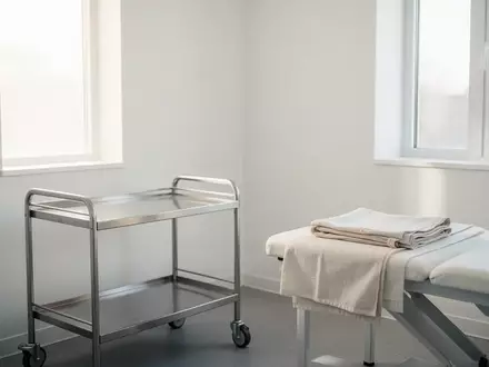 Ein heller, steriler Untersuchungsraum in einer Klinik mit einfallendem Tageslicht und einem leeren medizinischen Rollwagen. - Foto: ĂĽber boerse-global.de