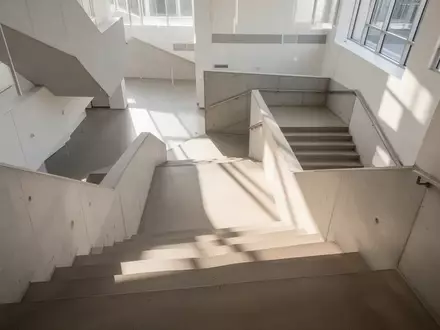 Ein minimalistisches Treppenhaus mit hellem, natürlichem Licht und Architektur aus Beton, die Bewegung im Alltag symbolisiert. - Foto: über boerse-global.de