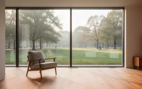 Ein helles, modernes Wohnzimmer mit Blick in einen Park, das eine ruhige und unterstützende Wohnumgebung für Senioren darstellt. - Foto: über boerse-global.de