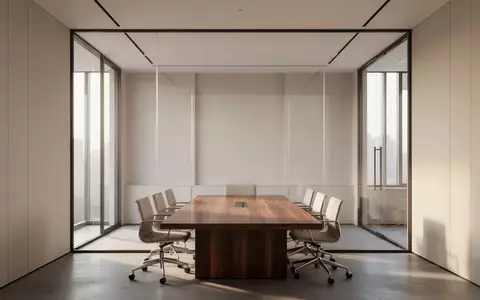 Ein minimalistischer, moderner Konferenzraum mit einem leeren Holztisch in einem hellen, architektonisch schlichten Büro. - Foto: über boerse-global.de