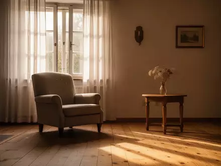 Ein sonnendurchflutetes, leeres Wohnzimmer mit einem Sessel am Fenster und einer Blumenvase auf einem Beistelltisch. - Foto: über boerse-global.de