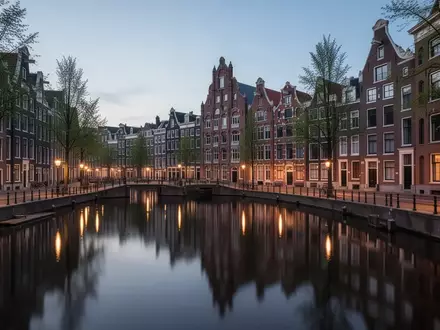Amsterdamer Grachten bei Dämmerung mit historischer Architektur und Spiegelungen im Wasser - Foto: über boerse-global.de