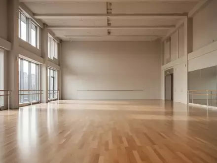 Ein heller, leerer Tanzsaal mit poliertem Holzboden und großen Fenstern, durch die natürliches Licht in den Raum fällt. - Foto: über boerse-global.de