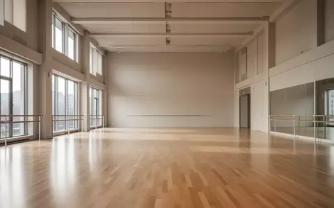 Ein heller, leerer Tanzsaal mit poliertem Holzboden und großen Fenstern, durch die natürliches Licht in den Raum fällt. - Foto: über boerse-global.de