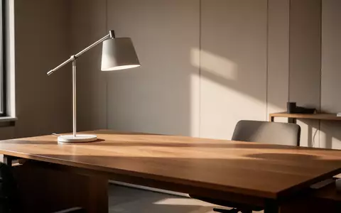 Ein minimalistischer, moderner Arbeitsplatz mit einem Holztisch und einer ausgeschalteten Schreibtischlampe. - Foto: über boerse-global.de