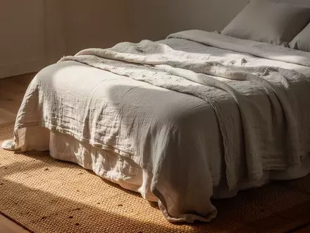 Ein minimalistisch eingerichtetes Schlafzimmer mit Bettwäsche aus Naturfasern und einem Sisalteppich in natürlichem Licht. - Foto: über boerse-global.de