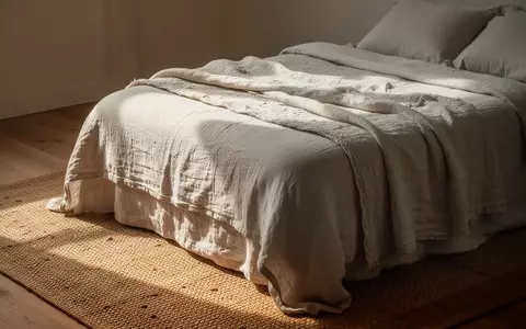 Ein minimalistisch eingerichtetes Schlafzimmer mit Bettwäsche aus Naturfasern und einem Sisalteppich in natürlichem Licht. - Foto: über boerse-global.de