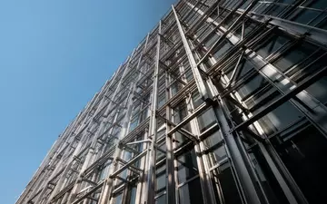 Moderne Hochhausfassade mit präziser Stahl-Glas-Konstruktion bei klarem Himmel. - Foto: über boerse-global.de