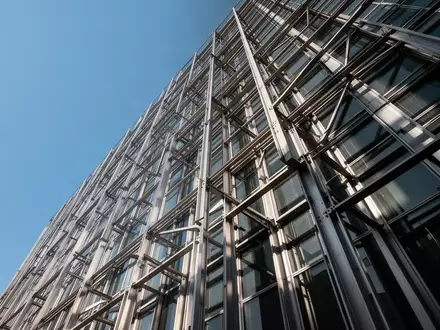 Moderne Hochhausfassade mit präziser Stahl-Glas-Konstruktion bei klarem Himmel. - Foto: über boerse-global.de