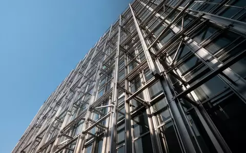 Moderne Hochhausfassade mit präziser Stahl-Glas-Konstruktion bei klarem Himmel. - Foto: über boerse-global.de