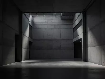 Ein minimalistischer, leerer Innenraum eines modernen Industriegebäudes mit Betonwänden und tiefen Schatten. - Foto: über boerse-global.de
