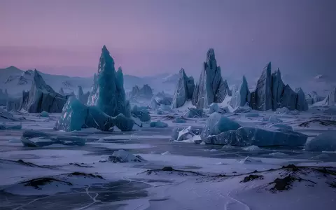 Eine weite, arktische Tundra mit zerklüfteten, kristallinen Eisformationen unter einem dämmrigen, violetten Himmel. - Foto: über boerse-global.de