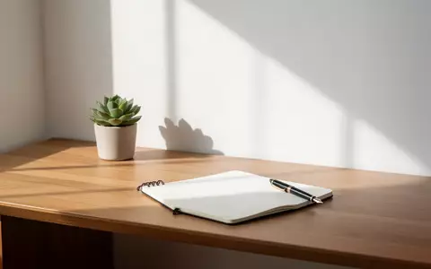 Ein minimalistischer Schreibtisch mit einem Notizbuch und einer Pflanze bei natürlichem Lichteinfall. - Foto: über boerse-global.de