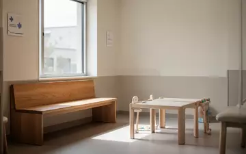 Ein ruhiger, minimalistischer Wartebereich in einer Kinderarztpraxis mit Tageslicht und leeren Sitzmöbeln. - Foto: über boerse-global.de