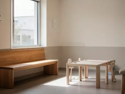 Ein ruhiger, minimalistischer Wartebereich in einer Kinderarztpraxis mit Tageslicht und leeren Sitzmöbeln. - Foto: über boerse-global.de
