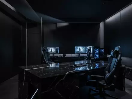 Ein minimalistisch gestalteter, dunkler Gaming-Raum mit indirekter Beleuchtung und einer glatten, reflektierenden Tischoberfläche. - Foto: über boerse-global.de