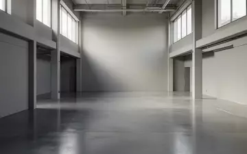 Ein minimalistischer, leerer Industrieraum mit poliertem Betonboden und neutralen Wänden bei natürlichem Tageslicht. - Foto: über boerse-global.de