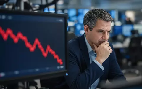 Ein besorgter Börsenhändler blickt auf einen Monitor mit einem fallenden Aktienkurs. - Foto: über boerse-global.de