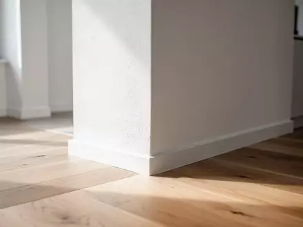 Ein minimalistischer Wohnraum mit Fokus auf eine saubere Wand und einen Holzboden bei natürlichem Lichteinfall. - Foto: über boerse-global.de