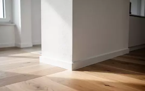 Ein minimalistischer Wohnraum mit Fokus auf eine saubere Wand und einen Holzboden bei natürlichem Lichteinfall. - Foto: über boerse-global.de