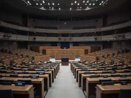 Ein leerer, modern gestalteter Plenarsaal des Europäischen Parlaments mit unbesetzten Sitzreihen in gedimmtem Licht. - Foto: über boerse-global.de