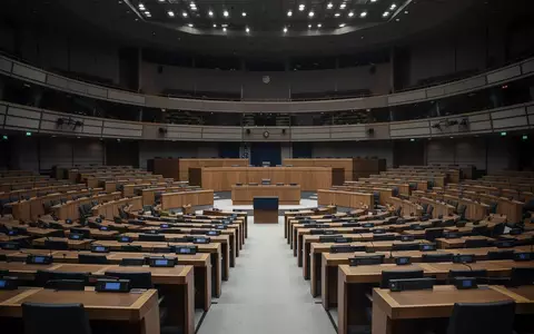 Ein leerer, modern gestalteter Plenarsaal des Europäischen Parlaments mit unbesetzten Sitzreihen in gedimmtem Licht. - Foto: über boerse-global.de