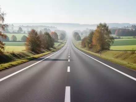 Eine leere, moderne Autobahn erstreckt sich durch eine grüne europäische Landschaft bei hellem Tageslicht. - Foto: über boerse-global.de