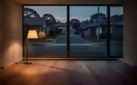 Ein minimalistisch eingerichtetes, leeres Wohnzimmer in der Abenddämmerung mit langen Schatten auf dem Boden. - Foto: über boerse-global.de