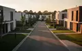 Eine ruhige Wohnstraße mit moderner Architektur und gepflegten Grünflächen im goldenen Licht des späten Nachmittags. - Foto: über boerse-global.de