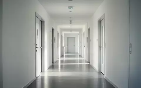Ein minimalistischer, leerer Flur in einer modernen Schweizer Klinik mit hellem Tageslicht und sauberen, weißen Wänden. - Foto: über boerse-global.de