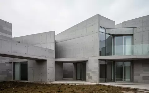 Ein minimalistisches Wohngebäude mit klaren architektonischen Linien und grauen Betonwänden bei bewölktem Himmel. - Foto: über boerse-global.de