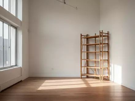 Ein minimalistisch eingerichteter, lichtdurchfluteter Wohnraum mit hohen Decken und einem Bambusregal in der Ecke. - Foto: über boerse-global.de