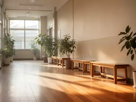 Ein heller, ruhiger Flur in einer Schule mit Holzboden, großen Fenstern und Pflanzen. - Foto: über boerse-global.de