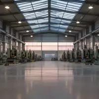 Eine leere, moderne Industriehalle mit stillstehenden Maschinen und natürlichem Lichteinfall. - Foto: über boerse-global.de