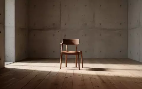 Ein minimalistischer, leerer Raum mit einem einzelnen Holzstuhl in natürlichem Sonnenlicht, der Stille und Reduktion symbolisiert. - Foto: über boerse-global.de