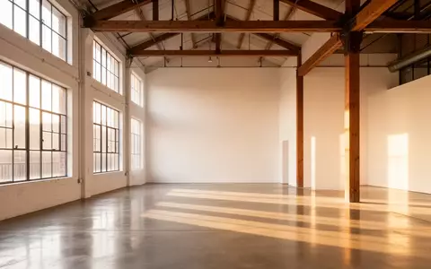 Ein heller, minimalistischer Innenraum eines umgenutzten Gebäudes mit hohen Decken, Betonboden und natürlichem Lichteinfall. - Foto: über boerse-global.de