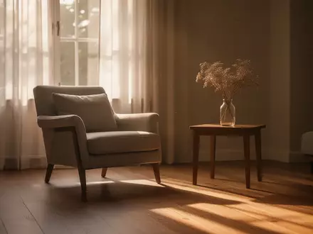 Ein ruhiges, sonnendurchflutetes Wohnzimmer mit einem bequemen Sessel und einer Blumenvase, das eine Atmosphäre der Stille vermittelt. - Foto: über boerse-global.de