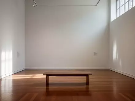 Ein heller, minimalistischer Galerieraum mit einer leeren Holzbank und sanftem Lichteinfall. - Foto: über boerse-global.de