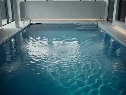Ein ruhiges, blaues Schwimmbecken mit klarem Wasser und sanften Lichtreflexen auf der Oberfläche. - Foto: über boerse-global.de