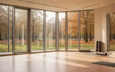 Ein heller, minimalistischer Bewegungsraum mit Holzboden und Blick in einen herbstlichen Park, ohne Personen oder Geräte. - Foto: über boerse-global.de
