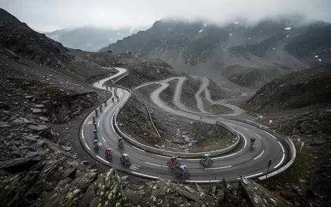 Eine steile, einsame Bergstraße in einer kargen Alpenlandschaft bei bedecktem Himmel. - Foto: über boerse-global.de