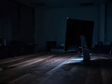 Ein dunkles, leeres Büro bei Nacht mit dem schwachen blauen Licht eines ausgeschalteten Computerbildschirms. - Foto: über boerse-global.de