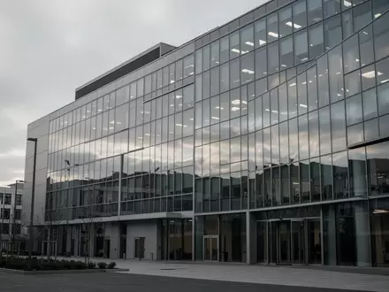Ein modernes Bürogebäude mit Glasfassade bei bewölktem Himmel ohne sichtbare Personen oder Beschilderung. - Foto: über boerse-global.de